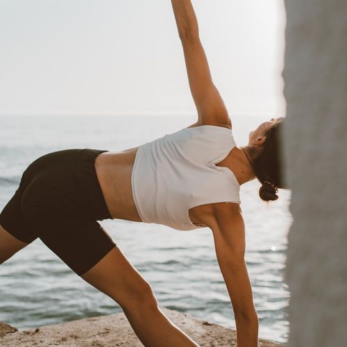 Person stretching gently outdoors during sunrise, feeling calm.